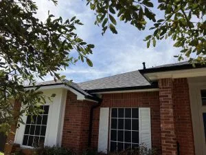 dark color gutters on red brick home with white shutters