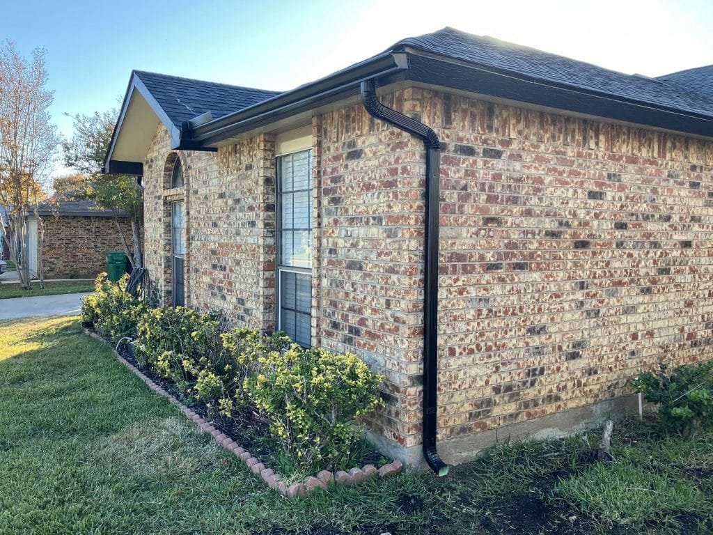 closeup photo of dark gutter on mottled brick home