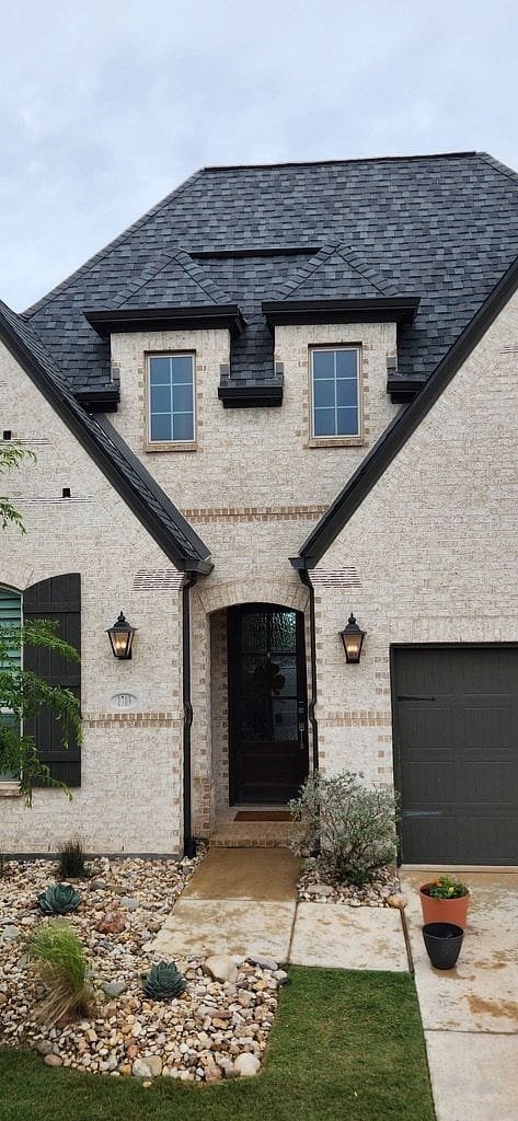 entry way view of dark color gutters on blonde brick home